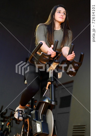 Woman in gym spinning on fitness bike. Woman in gym spinning on fitness bike. 72634101
