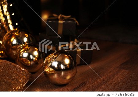 Black gift box with golden ribbon and big gold New Year balls on black 72636635