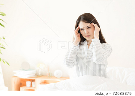寝室で目覚める若い女性 体調不良 の写真素材
