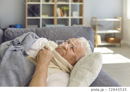 Sad senior man in scarf lying in bed with handkerchief under blanket and feeling ill Sad senior man in scarf lying in bed with handkerchief under blanket and feeling ill 72643535