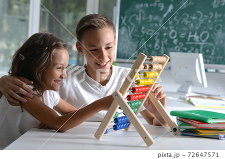 Cheerful brother and sister doing homework together Cheerful brother and sister doing homework together 72647571