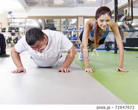an overweight young man doing push-ups together with a young lady an overweight young man doing push-ups together with a young lady 72647672