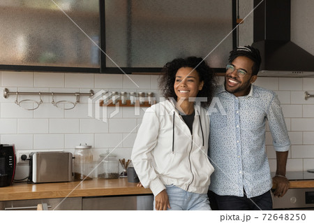Happy biracial couple dreaming in new home kitchen Happy biracial couple dreaming in new home kitchen 72648250