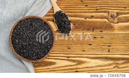 Rice berry in a bowl and spoon on a wooden table. 72648706