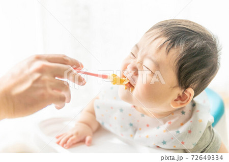 窓辺でベビーチェアに座って離乳食を食べる赤ちゃん 窓辺でベビーチェアに座って離乳食を食べる赤ちゃん 72649334