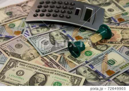 Calculator and hourglass lies on the dollars. 72649903