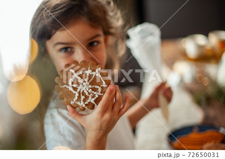 Little cute girl decorates gingerbread with sugar icing. Preparation for Christmas concept. Little cute girl decorates gingerbread with sugar icing. Preparation for Christmas concept. 72650031
