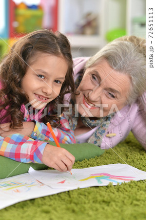 Portrait of grandmother and granddaughter drawing together 72651113
