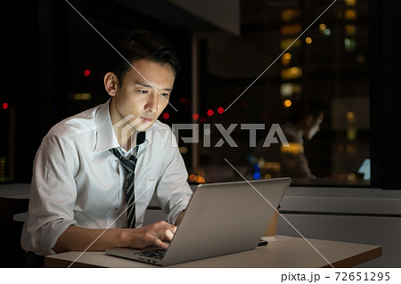 オフィスで夜遅くまで残業をするビジネスマン 72651295