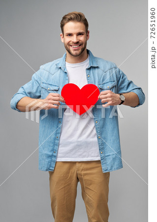 Portrait of charming man hold hand paper heart shaped card wear casual style shirt isolated over grey background 72651960
