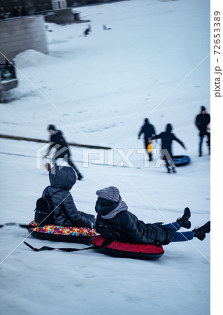 children having fun riding on tube in winter slide 72653389