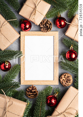 Christmas holidays composition with picture frame mockup. Red baubles, gifts and fir-tree branches. Christmas holidays composition with picture frame mockup. Red baubles, gifts and fir-tree branches. 72654559