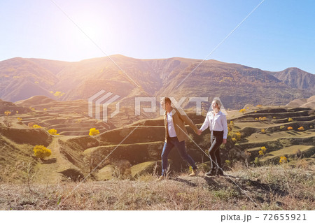 Young couple holding hands is walking on the background of mountain terraces on a sunny day 72655921