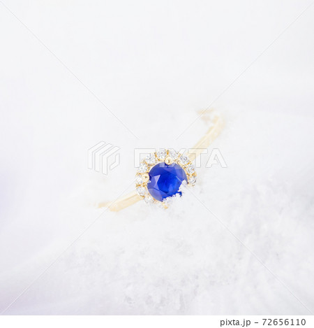 Gold ring with blue sapphire on white snow background Gold ring with blue sapphire on white snow background 72656110
