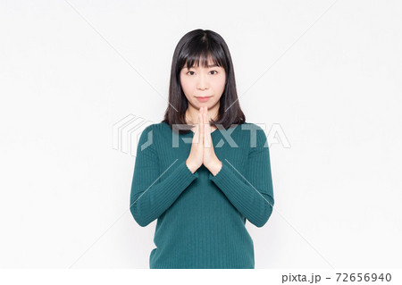 白背景の前でお願いのジェスチャーをする女性 白背景の前でお願いのジェスチャーをする女性 72656940