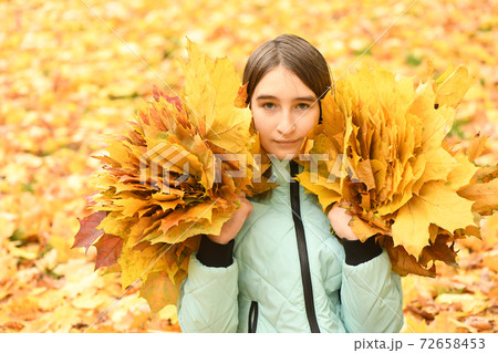 Pre-adolescent girl holds a bouquet of autumn leaves in her hand Pre-adolescent girl holds a bouquet of autumn leaves in her hand 72658453