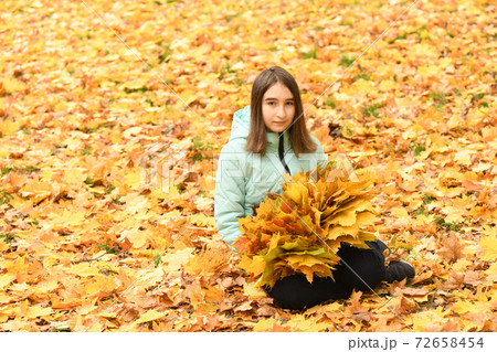 Pre-adolescent girl holds a bouquet of autumn leaves in her hand Pre-adolescent girl holds a bouquet of autumn leaves in her hand 72658454