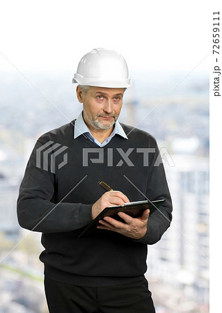 Mature architect looking on object. Mature architect looking on object. 72659111
