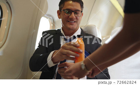 Businessman have orange juice served by an air hostess in airplane 72662824