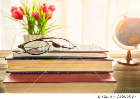 Reading glasses put on hardcover book beside the window Reading glasses put on hardcover book beside the window 72665037