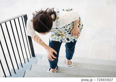 膝が痛くて階段を登ることが辛い女性の写真素材