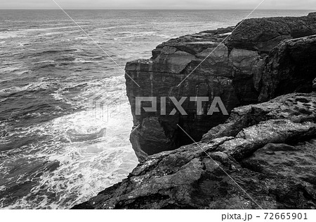 Black and white seascape of Irish cliffs battered by waves, Ireland 72665901
