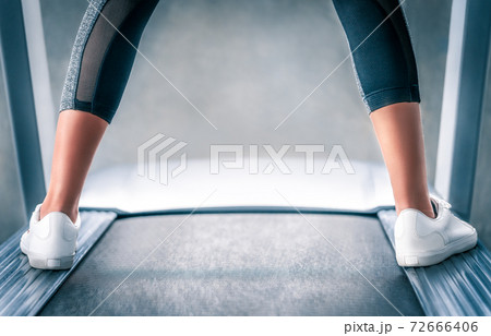Indoor runner legs is standing on the side of the treadmill while resting from jogging exercise. 72666406