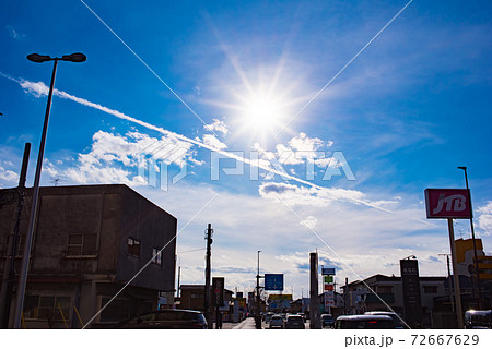 町の上空に広がる青い空と太陽 72667629