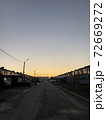 Yellow sunset in the small city. Road and city buildings silhouettes. 72669272
