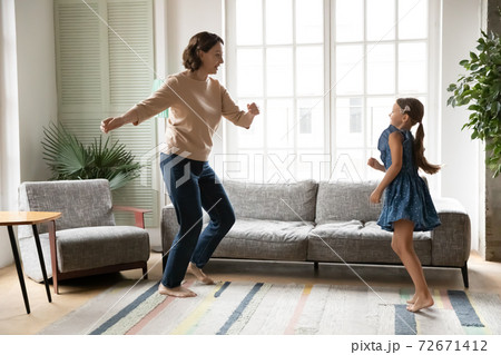 Overjoyed mature grandmother and little granddaughter dancing at home Overjoyed mature grandmother and little granddaughter dancing at home 72671412