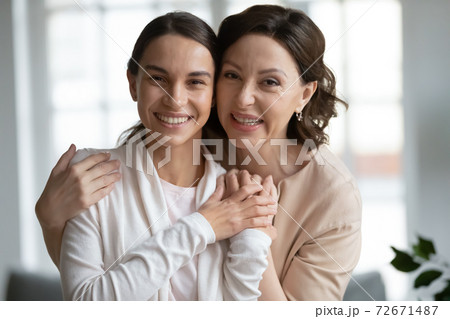 Head shot portrait smiling middle aged mother hugging grownup daughter 72671487