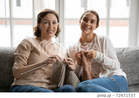 Head shot portrait smiling mature mother and grownup daughter knitting Head shot portrait smiling mature mother and grownup daughter knitting 72671537
