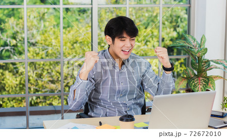 Asian man raising his arm up to celebrate celebrating success 72672010