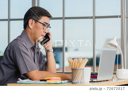 senior businessman sitting on desk office he using his mobile phone senior businessman sitting on desk office he using his mobile phone 72672017