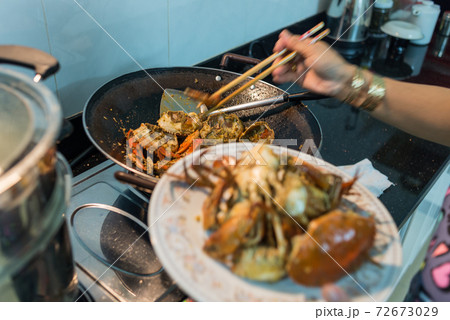 Woman cooking homemade spicy stir-fried crabs in kitchen at home 72673029