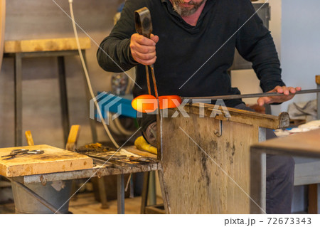 Artisan making glass blowing product under high fire at workshop 72673343
