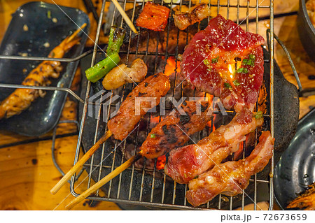 Marinated meat and skewers on flaming barbecue charcoal stove  72673659