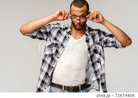Portrait of a young african american man wearing glasses with surprised expression on face Portrait of a young african american man wearing glasses with surprised expression on face 72674806