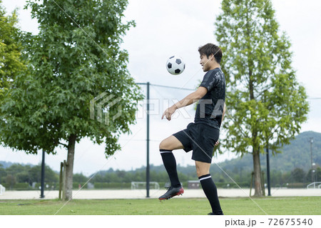 公園でサッカーをする若い男性 72675540