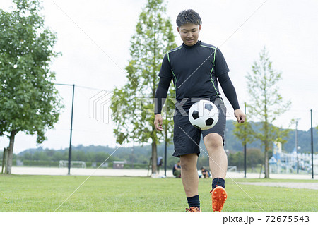 公園でサッカーをする若い男性 72675543