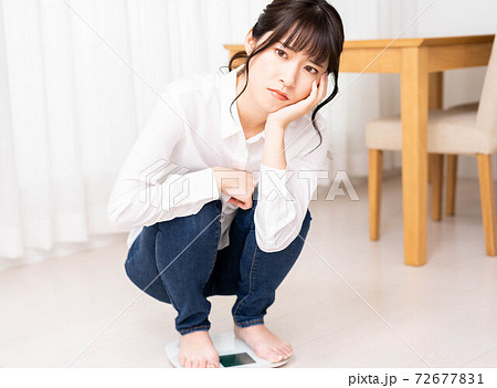 体重計に乗って悩む若い女性 72677831
