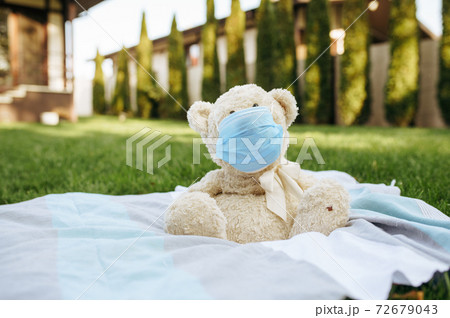 Teddy bear in protection mask sitting on a blanket 72679043