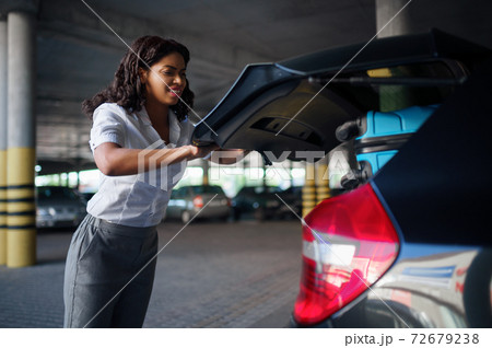Woman can't close trunk with suitcases, parking Woman can't close trunk with suitcases, parking 72679238