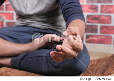 Young man meditating in the lotus pose, close up Young man meditating in the lotus pose, close up 72679458