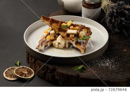 Viennese waffles with banana, mango, caramel and mint. Classic hot dessert Belgian waffles. Viennese waffles with banana, mango, caramel and mint. Classic hot dessert Belgian waffles. 72679648