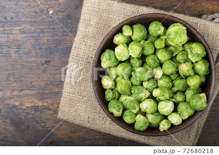 Fresh raw brussels sprouts in a bowl on a wooden table. 72680218