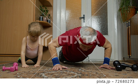 Child kid girl with senior grandfather in sportswear making sports workout push-up exercises at home Child kid girl with senior grandfather in sportswear making sports workout push-up exercises at home 72680273