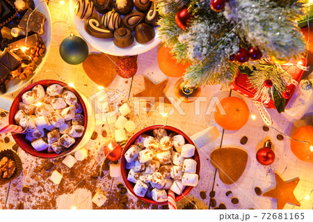 sweet food top view background for merry christmas or new year holiday decoration with night illumination - chocolate candies, tangerines, cookies, marshmallow and cocoa latte on white wood 72681165