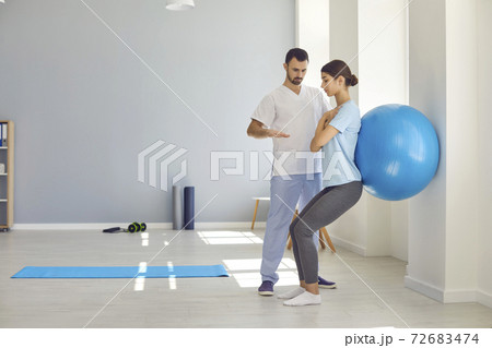 Professional osteopath controlling womans position during exercising with fitness ball Professional osteopath controlling womans position during exercising with fitness ball 72683474