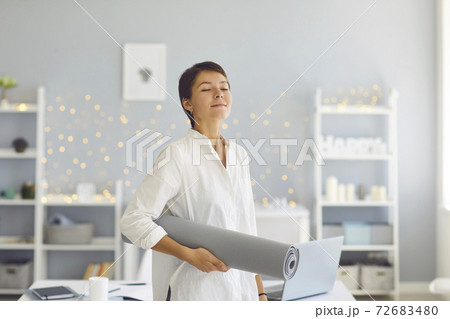 Relaxed woman standing with fitness mat in hand after meditating or yoga practice Relaxed woman standing with fitness mat in hand after meditating or yoga practice 72683480